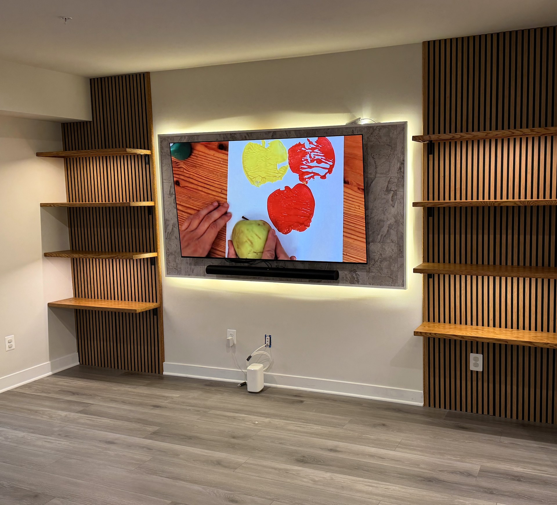 Custom TV media wall by Leo Build Co. — wood slat accent panels, floating shelves, LED backlight, Arcola VA